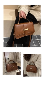 Detail of caramel brown crossbody bag featuring a golden H-shaped metal buckle and curved base