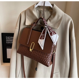 Detailed view of brown woven patchwork handbag with silk scarf and gold oval buckle