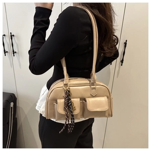 Detail of a beige leather shoulder bag featuring double flap pockets and a knot charm detail