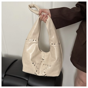 Close-up of cream leather bag featuring silver star-shaped rivet studs and soft texture