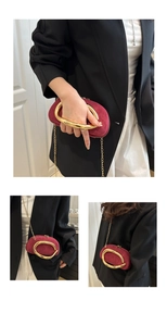 Macro detail of wine red suede mini bag featuring artistic gold circular handle and chain