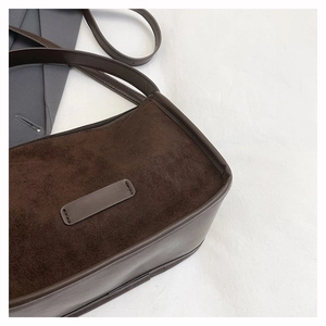 Close-up of brown suede and smooth leather texture on a stylish shoulder handbag