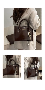 Détail du sac fourre-tout en cuir marron foncé avec logo doré et bijou de sac chic