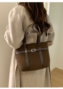 Close-up of brown knit tote bag with leather straps and silver metal buckle detail
