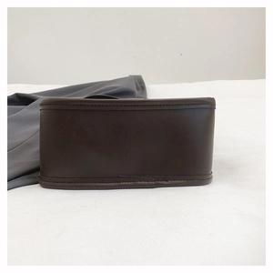 Detail view of the deep brown leather bag showing reinforced stitching and a wide base