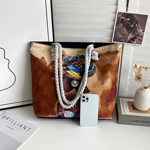 Detail of canvas tote bag showing African print and rope handle next to a smartphone