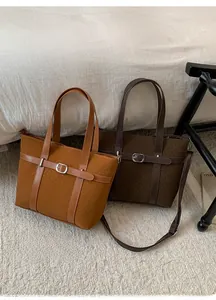 Detail of wool tote bags in brown and coffee with leather belt buckle and shoulder straps