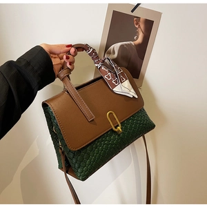 Detail of color-block handbag with green woven texture and scarf-wrapped handle