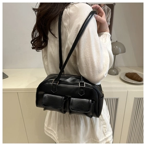 Detail view of black PU leather shoulder bag with gold buckles and dual front flap pockets