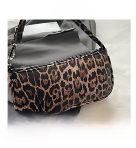 Close-up of leopard print underarm bag featuring silver metal buckle and top zipper detail