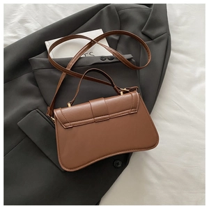 Detail of caramel brown quilted shoulder bag with top handle and gold-tone metal hardware