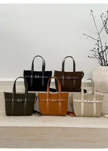 Close-up of five luxury monogram tote bags in various colors on marble steps