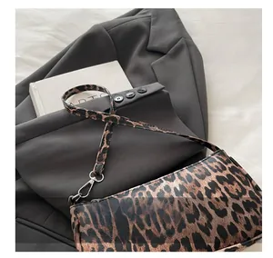 Detailed view of leopard print shoulder bag with black leather trim and silver hooks