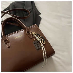 Détail d'un sac à main marron en PU avec texte doré et pendentif en forme de chocolat