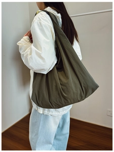 Detail view of large army green nylon tote bag with pleated texture on model