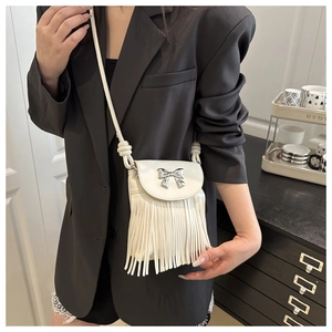Close-up of white PU leather crossbody bag featuring fringe tassels and a silver bow clasp