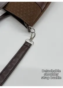 Detail of silver metal lobster clasp and detachable shoulder strap on brown woven bag