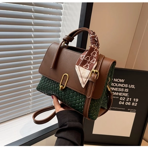 Detail of green woven handbag with brown leather flap and stylish silk scarf handle