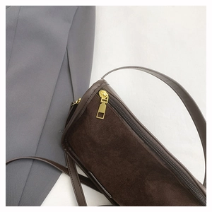 Close-up of matte dark brown suede handbag with leather trim and gold hardware details