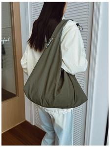 Detail of olive green nylon tote bag with pleated texture and long rope zipper puller