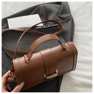 Detail of caramel brown PU leather handbag with metallic clasp and fine lychee texture