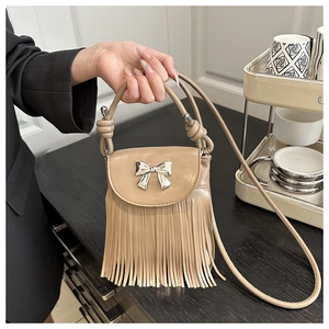 Detail of beige fringe crossbody bag with silver bow accent and knotted handle strap