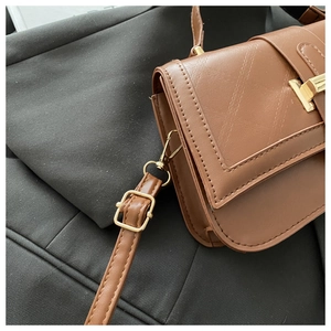 Close-up of brown pebbled leather texture with diagonal quilting and golden T-shaped lock