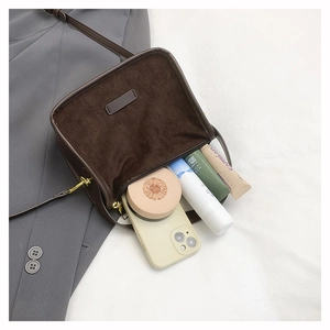 Detail view of brown matte crossbody bag showing interior storage for phone and makeup