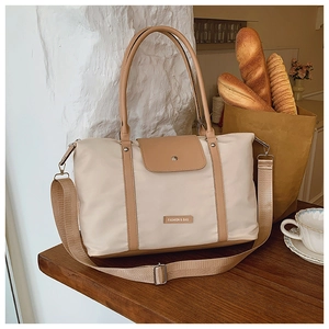 Close-up of beige nylon tote bag with leather straps and front pocket detail