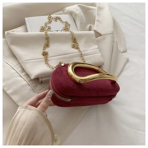 Détail du mini sac boîte en velours bordeaux avec poignée dorée et bandoulière chaîne