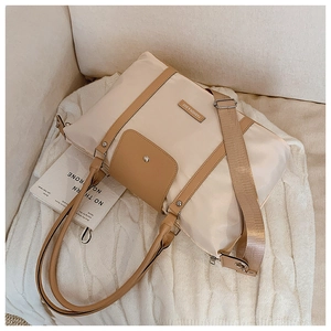 Close-up of cream nylon tote bag with leather trim and fashion metal plaque on knit fabric