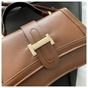 Close-up of brown quilted leather bag with gold buckle and diamond stitching detail