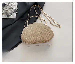 Detail view of champagne gold evening bag with metal ring handle and phone size reference