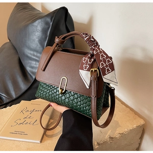 Detail of fashion crossbody bag with green weaving, leather texture, and silk scarf handle