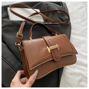 Detail of caramel brown PU leather crossbody bag with golden clasp and adjustable strap