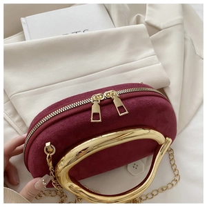 Détail d'un sac de soirée en daim bordeaux avec poignée en métal doré et double fermeture