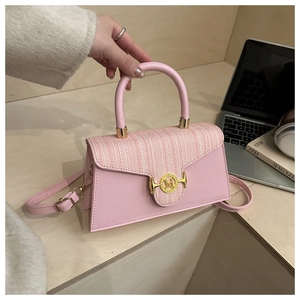 Nahaufnahme der rosa Tweed-Handtasche mit goldenem M-Verschluss auf einem Holztisch