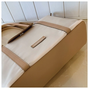 Macro shot of durable beige canvas tote bag with brown leather accents and brand patch