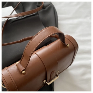 Close-up of brown textured leather handbag featuring golden metal hardware and handle details