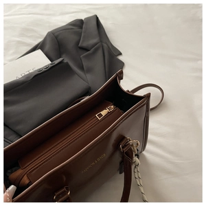 Détails d'un sac à main en cuir marron foncé avec ferrures dorées et lettrage de mode