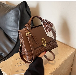 Close-up of brown textured woven patchwork bag with silk scarf and gold U-shaped buckle