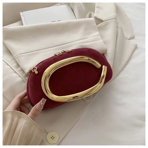 Détails d'un sac de soirée en daim bordeaux avec poignée dorée en métal liquide texturé