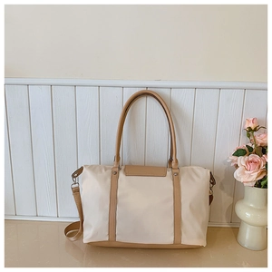 Detail of canvas tote bag showing beige nylon fabric with khaki leather straps and metal rivets
