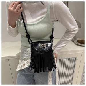 Detail of black PU crossbody bag featuring silver metal bow and elegant long tassels
