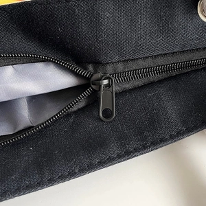 Detail of durable black canvas bag showing reinforced stitching and smooth metal zipper