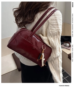 Close-up of deep burgundy glossy leather tote bag with stylish beaded tassel detail