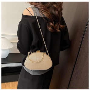 Detail of elegant gold evening clutch bag featuring a metallic handle and long chain strap