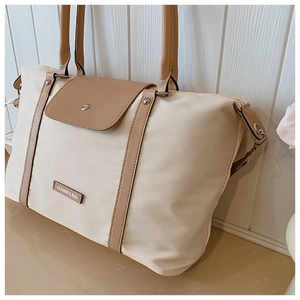Macro shot of beige canvas tote bag with brown leather straps and metal rivets