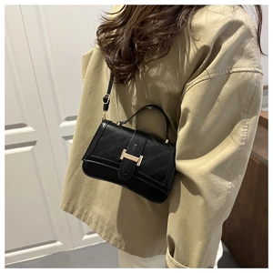 Close-up of black quilted leather bag featuring a gold H-shaped metal buckle detail