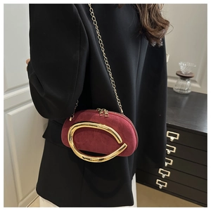 Detail of burgundy suede evening bag with large gold C-metal ring and chain strap